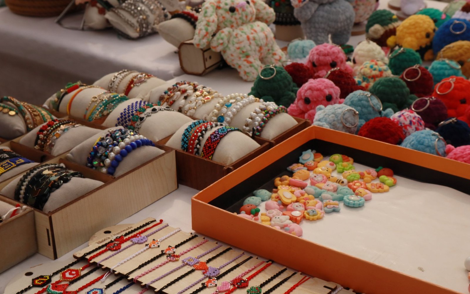 Beaded bracelets, crocheted octopus keychains, and colorful charm trinkets displayed on a market table