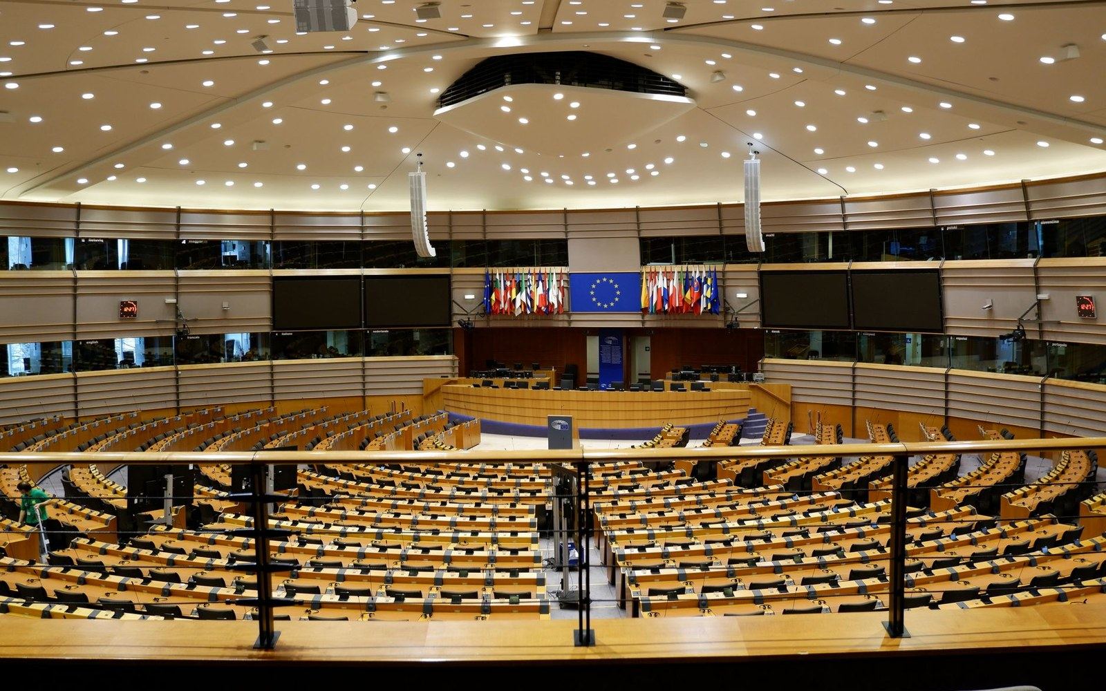 Empty rows of desks fill the European Parliament's hemicycle beneath EU member state flags