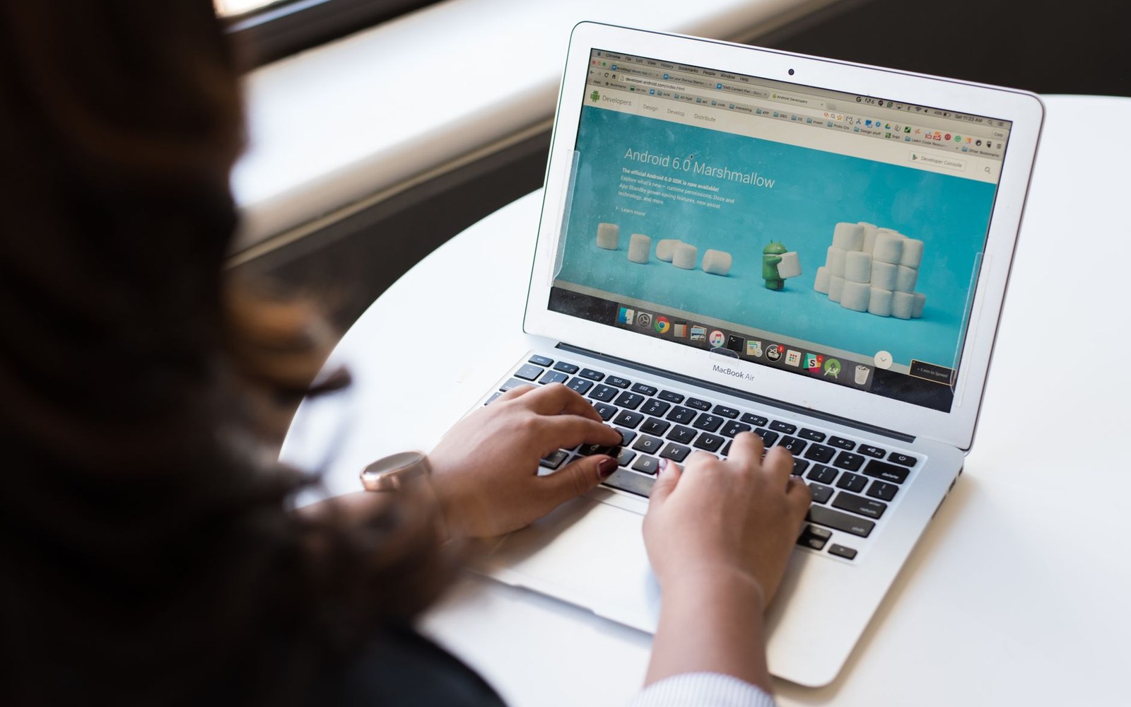 Person typing on a MacBook Air displaying the Android 6.0 Marshmallow webpage