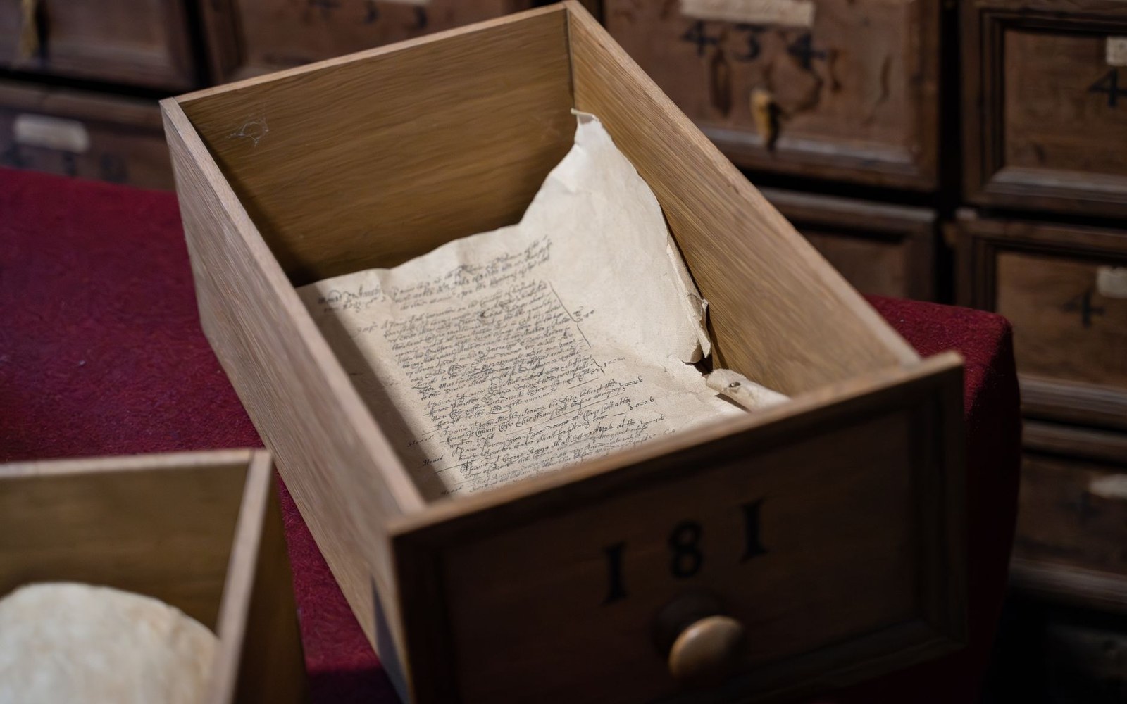 Handwritten manuscript pages inside an open wooden archive drawer numbered 181