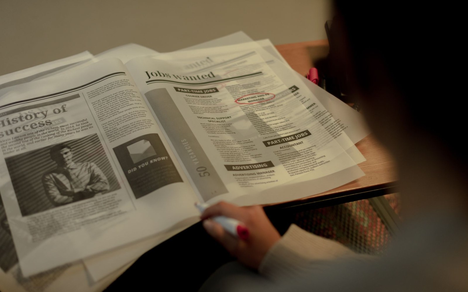 A person circles a listing in the "jobs wanted" section of a newspaper
