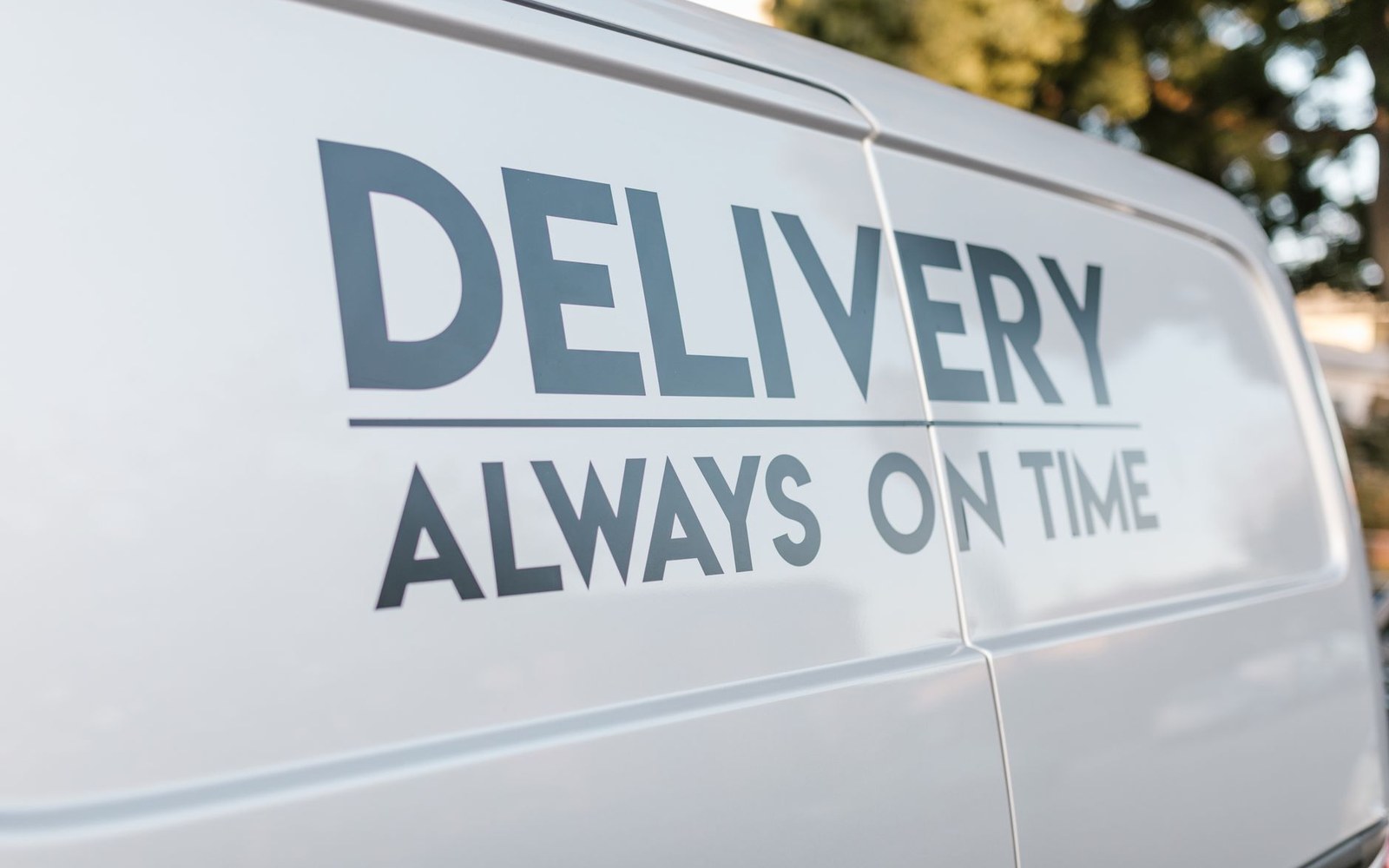 Close-up of a white van's side panel reading "delivery always on time"
