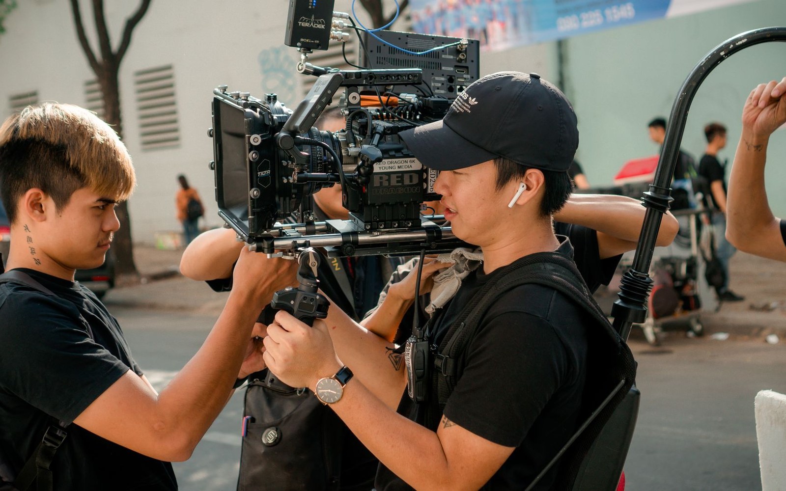 Two crew members adjust a professional cinema camera rig on a city street shoot